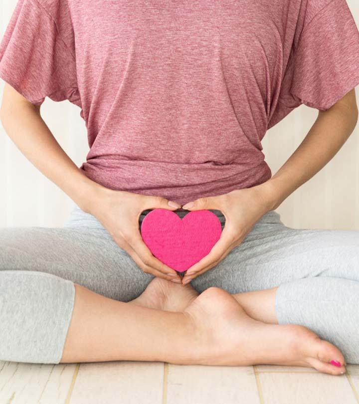 A woman holding up a heart in front of her lower tummy