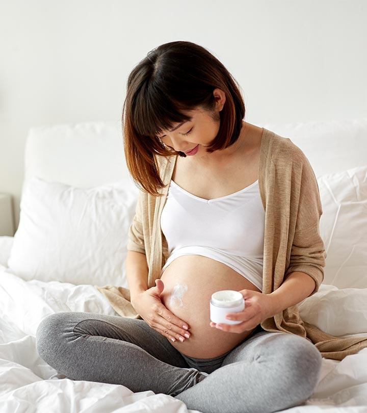 Pregnant woman applying stretch mark cream