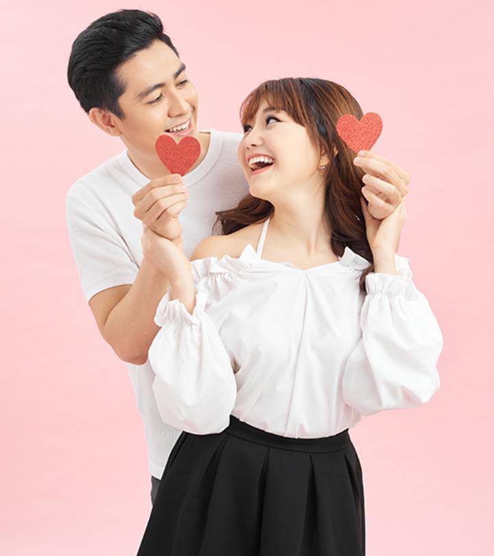 A young couple holding little hearts and looking at each other cheerfully