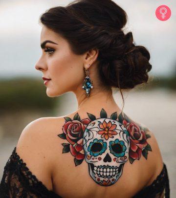 A woman with a colorful Day of the Dead skull tattoo on her back