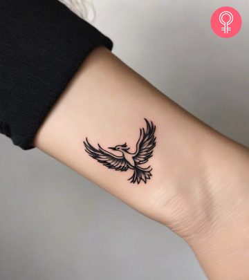A woman with a minimalist tattoo of a Phoenix in black ink.