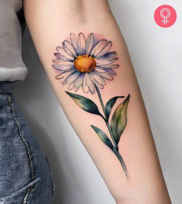 A daisy birth flower tattoo on the upper arm