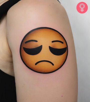 A sad girl tattoo on the upper arm