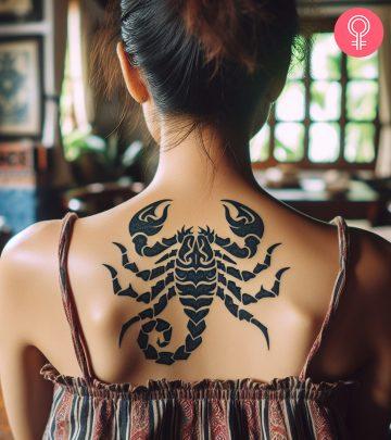 A tribal scorpion tattoo on a woman’s upper back A tribal scorpion tattoo on a woman’s upper back