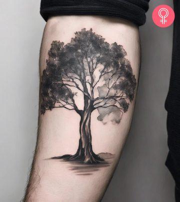 A man wearing a eucalyptus tree tattoo on his lower arm A man wearing a eucalyptus tree tattoo on his lower arm