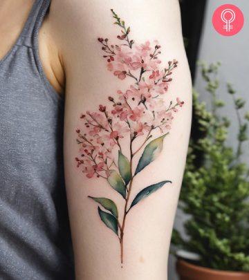 A watercolor tattoo of baby’s breath on a woman’s upper arm A watercolor tattoo of baby’s breath on a woman’s upper arm
