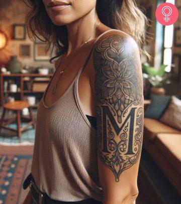 M tattoo with floral patterns on the upper arm M tattoo with floral patterns on the upper arm