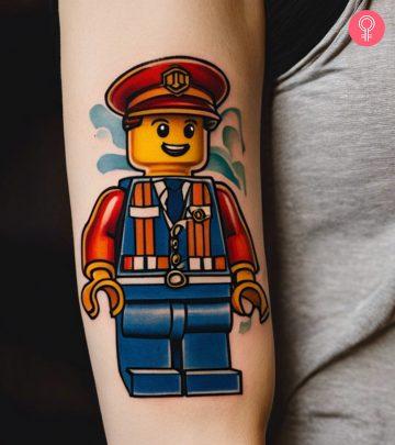 A woman with a colored Emmet, from The LEGO Movie, tattoo on the upper arm A woman with a colored Emmet, from The LEGO Movie, tattoo on the upper arm