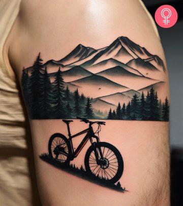 Man with a bike and mountains tattoo on the upper arm Man with a bike and mountains tattoo on the upper arm
